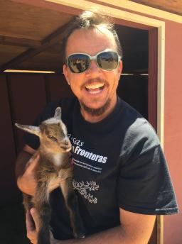 Poet TC Tolbert wears sunglasses and holds a baby goat