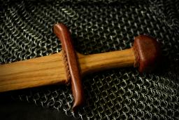 Wooden sword resting against gray chain mail / photo by Bronwyn Erb