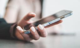Closeup of a manicured hand holding a smart phone, photo by Jae Park