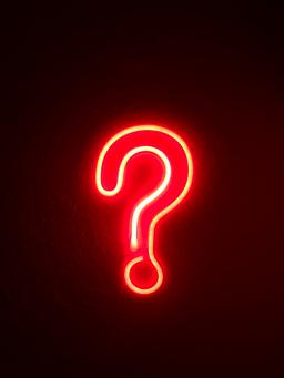 A red neon question mark against a black background, photo by Simone Secci
