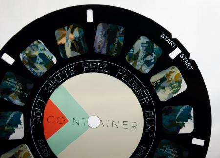 A black circle with small colored squares in grey, blue, green, and violet for use in a ViewMaster